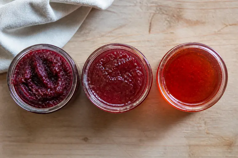 Drei Marmeladengläser zeigen unterschiedliche Konsistenzen: fest, glänzend und flüssig, wie man Marmelade richtig einkocht.
